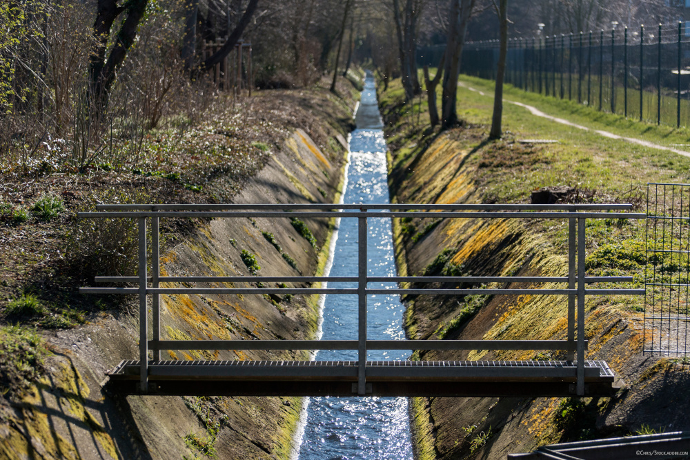 ein begradigter Bachlauf, über den eine Brücke führt